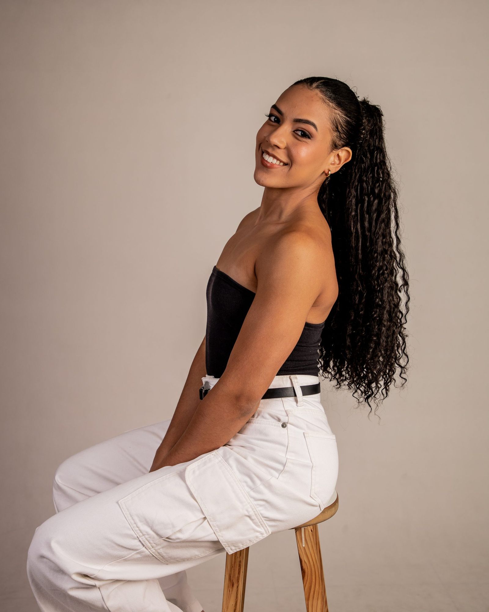 Analice Anastácio sentada no banquinho, ensaio de estúdio